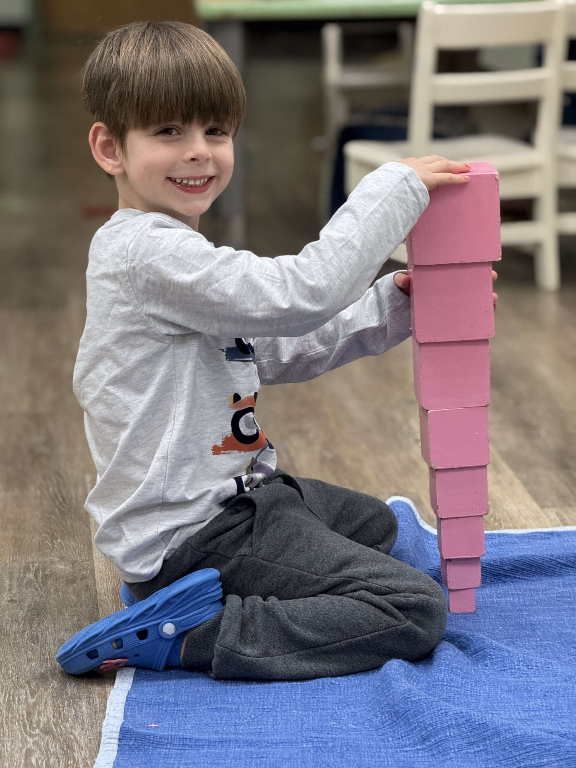 A smiling toddler building the Montessori pink tower