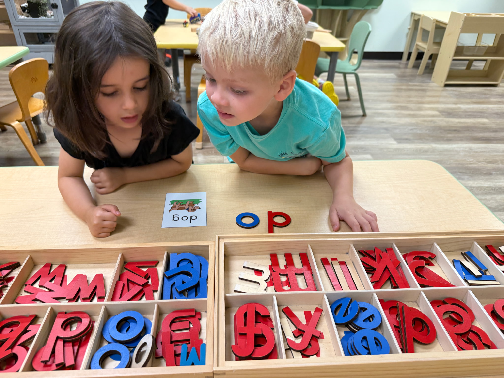 Two preschoolers spelling words with a Montessori movable alphabet at Mighty Sprouts